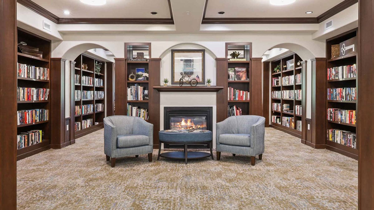 The library at Summerville Estates with shelves of books and comfortable seating